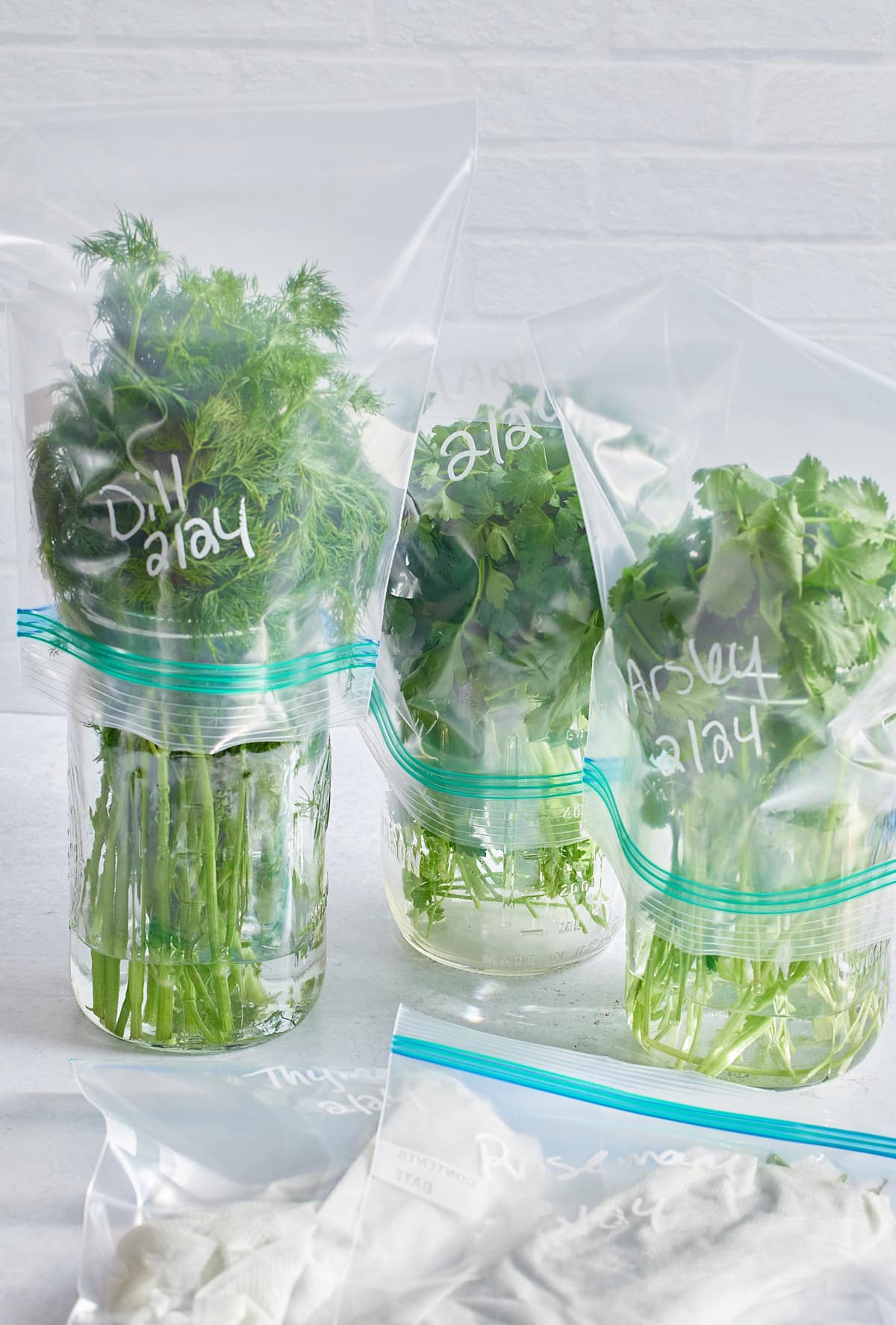 herbs in glass jars covered in plastic bags