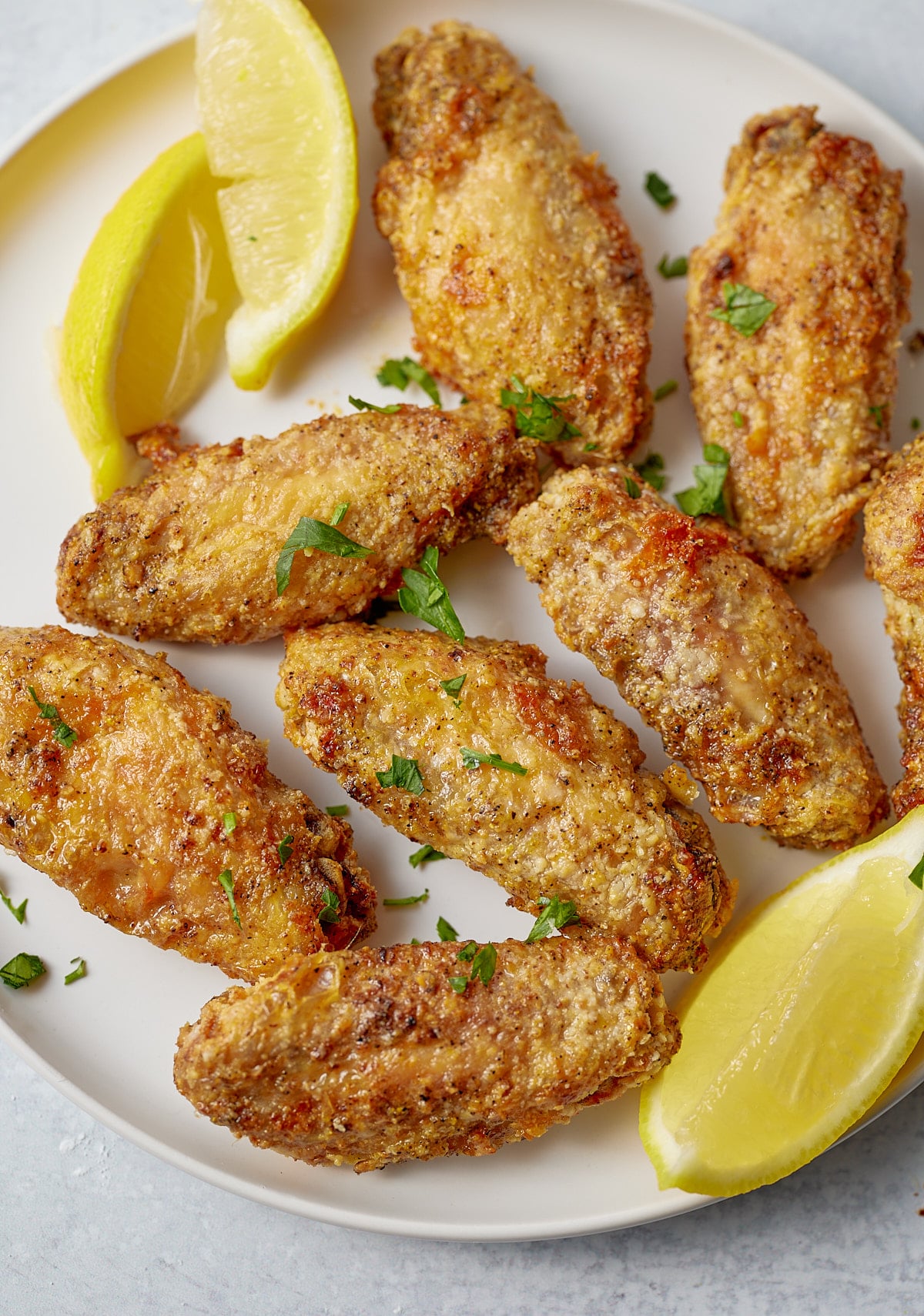 Lemon pepper wings served on a plate with lemon wedges.