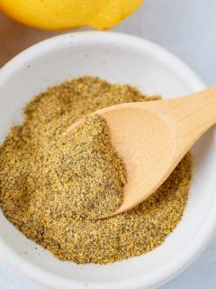 Lamon pepper seasoning in a shite bowl with a spoon.
