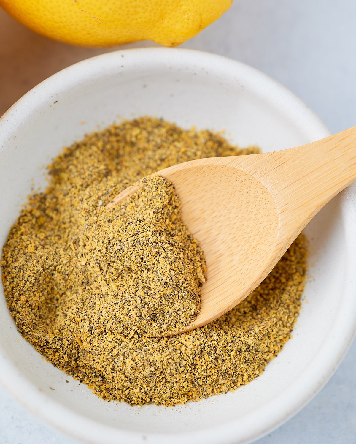 Lamon pepper seasoning in a shite bowl with a spoon.