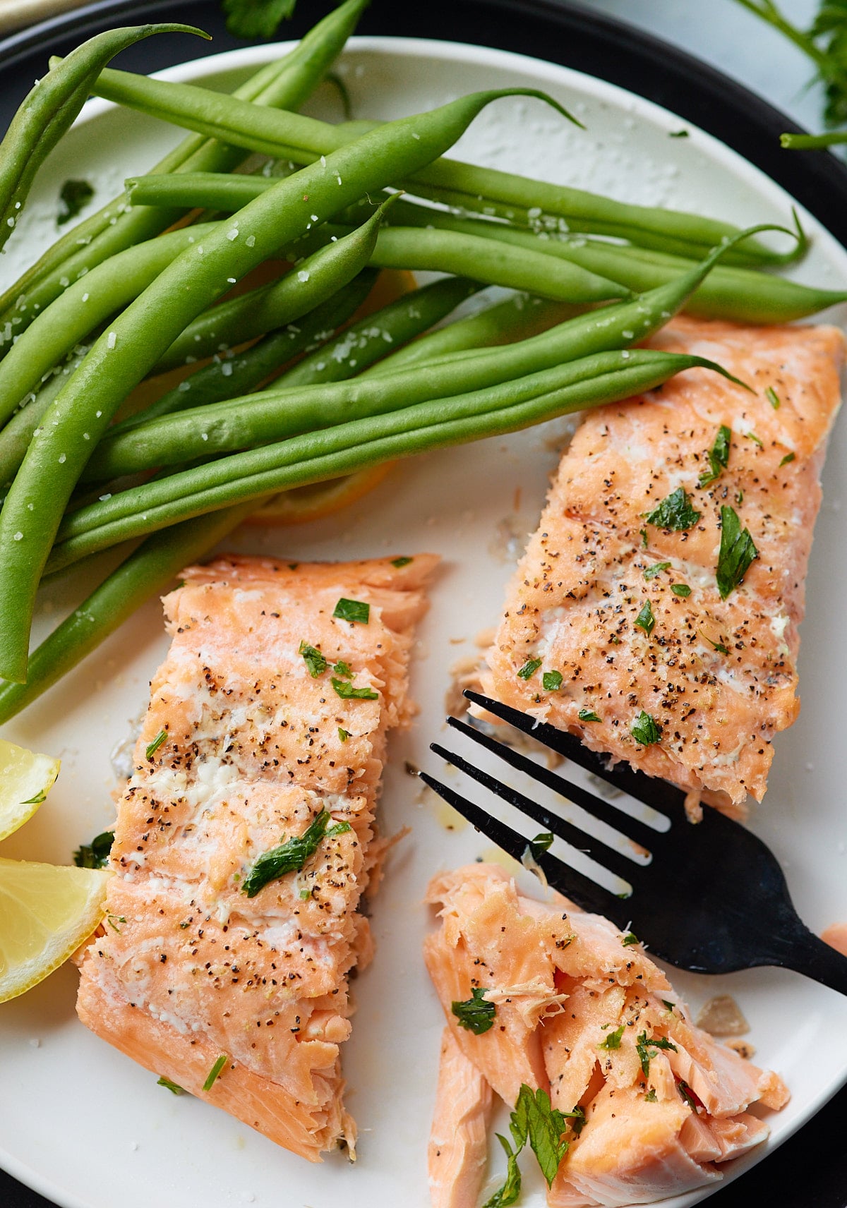 A fork cutting a baked salmon fillet.