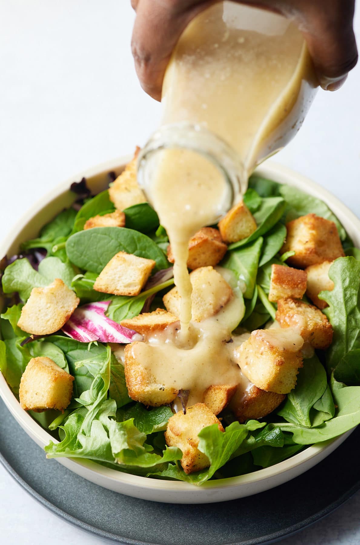 Sweet onion dressing being poured over a salad.