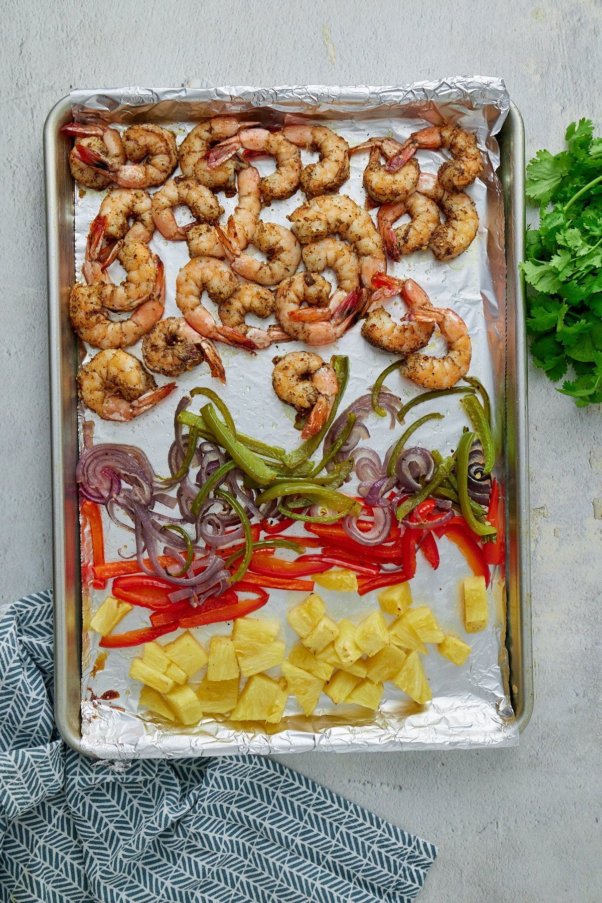 sheet pan lined with foil with shrimp, peppers, and pineapple