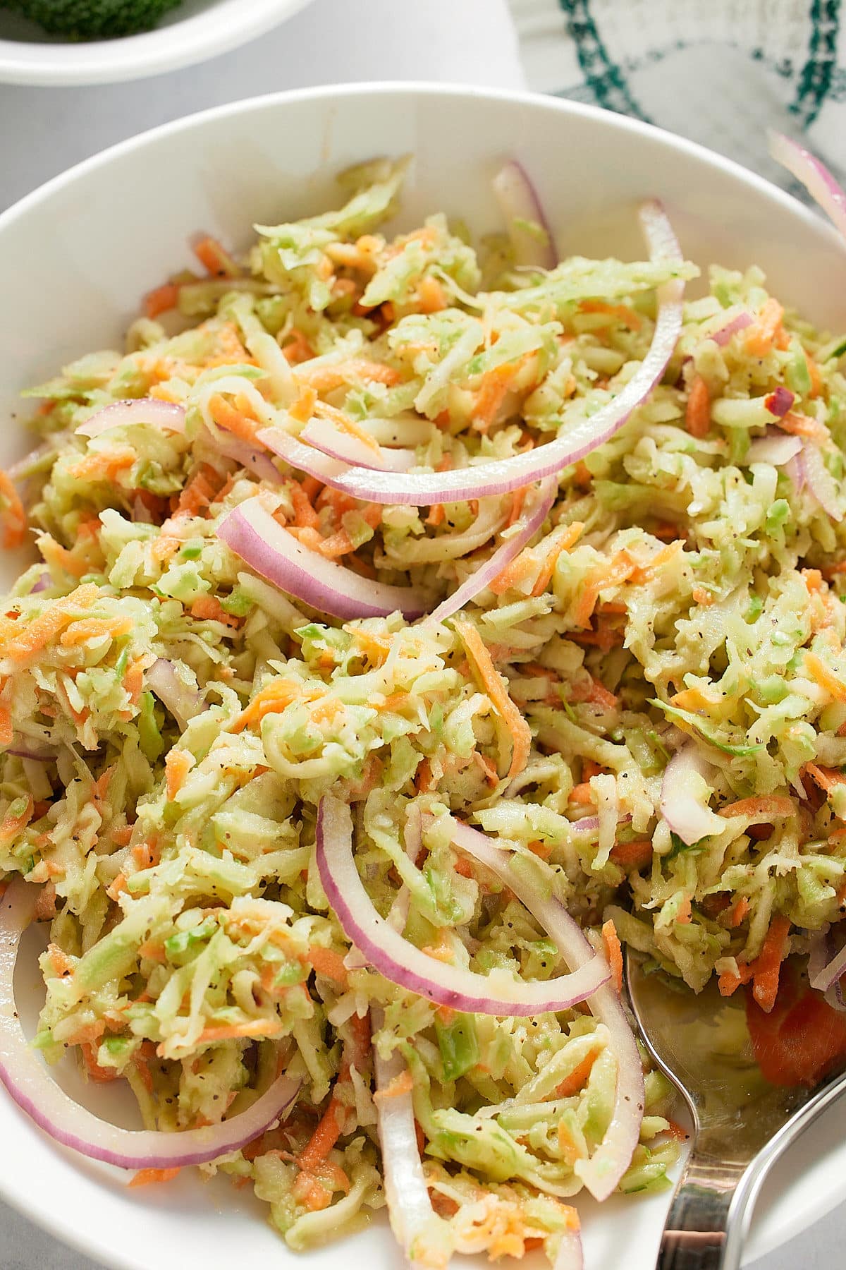 Close up of broccoli slaw in a white bowl.