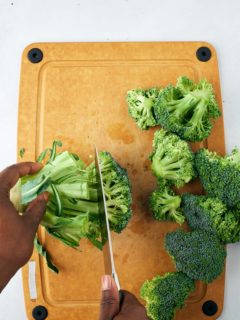 hand holding broccoli stem and cutting off florets