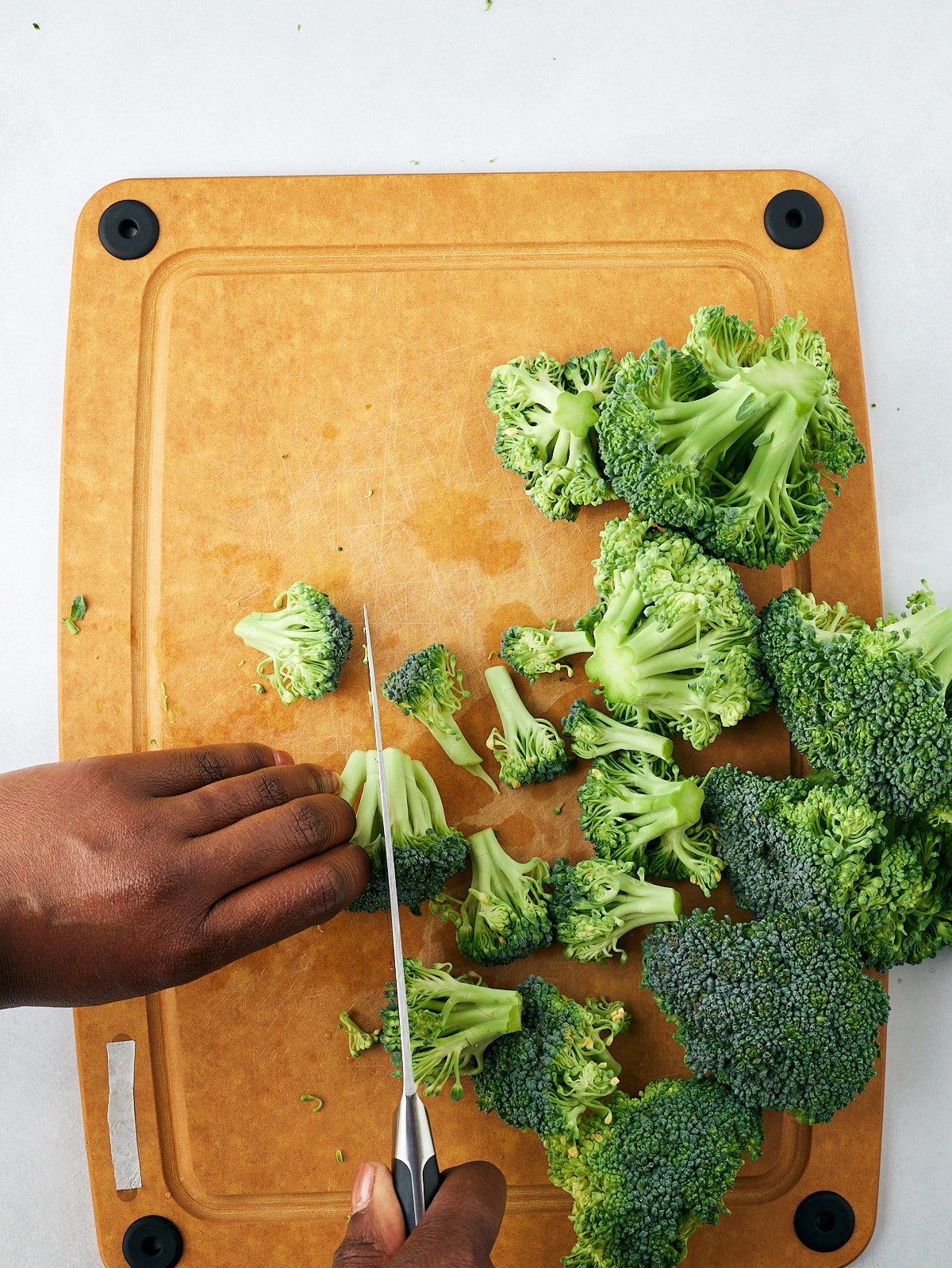 cutting broccoli florets in half on cooking board