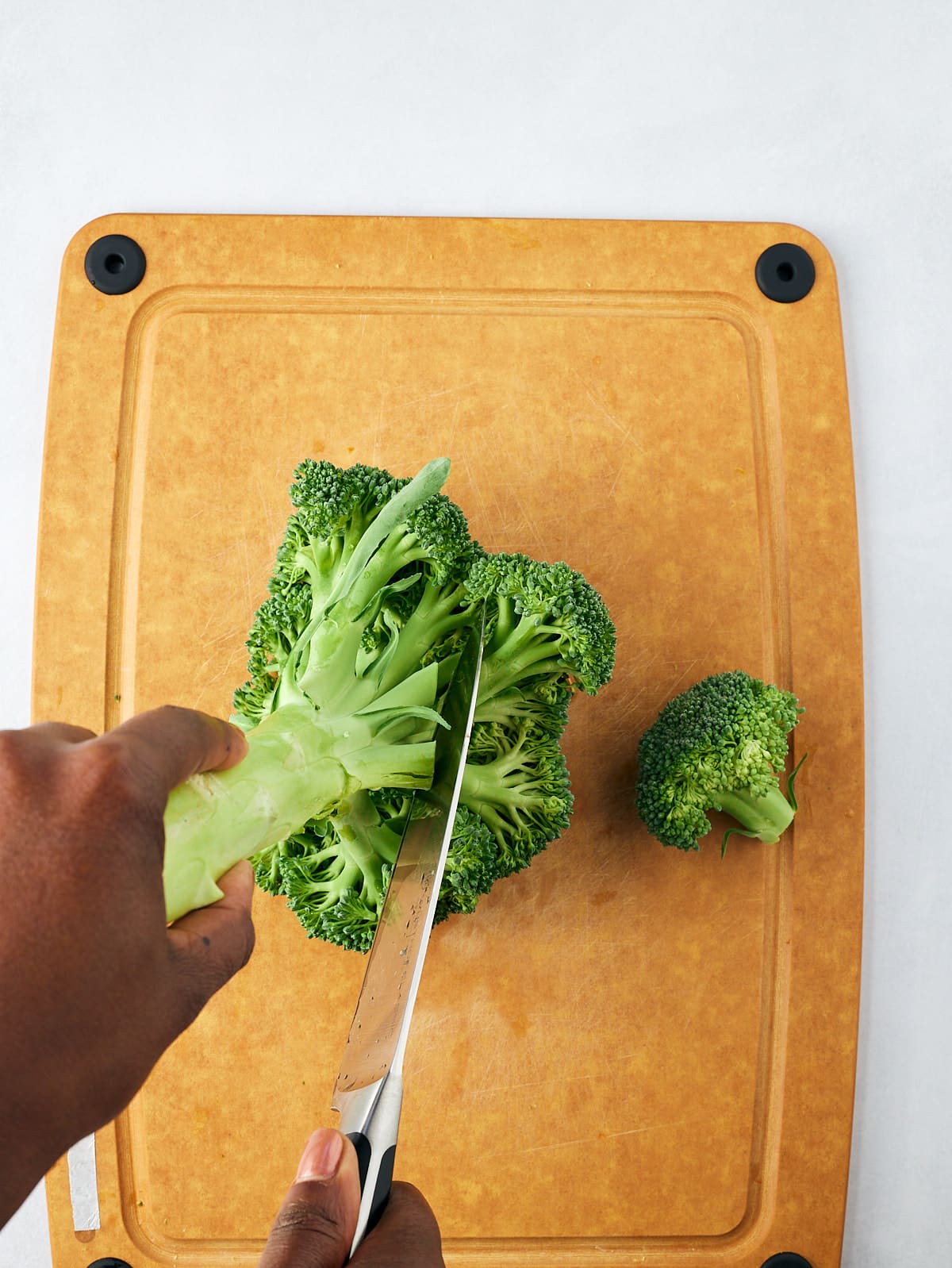 cutting broccoli florets in wooden cutting board