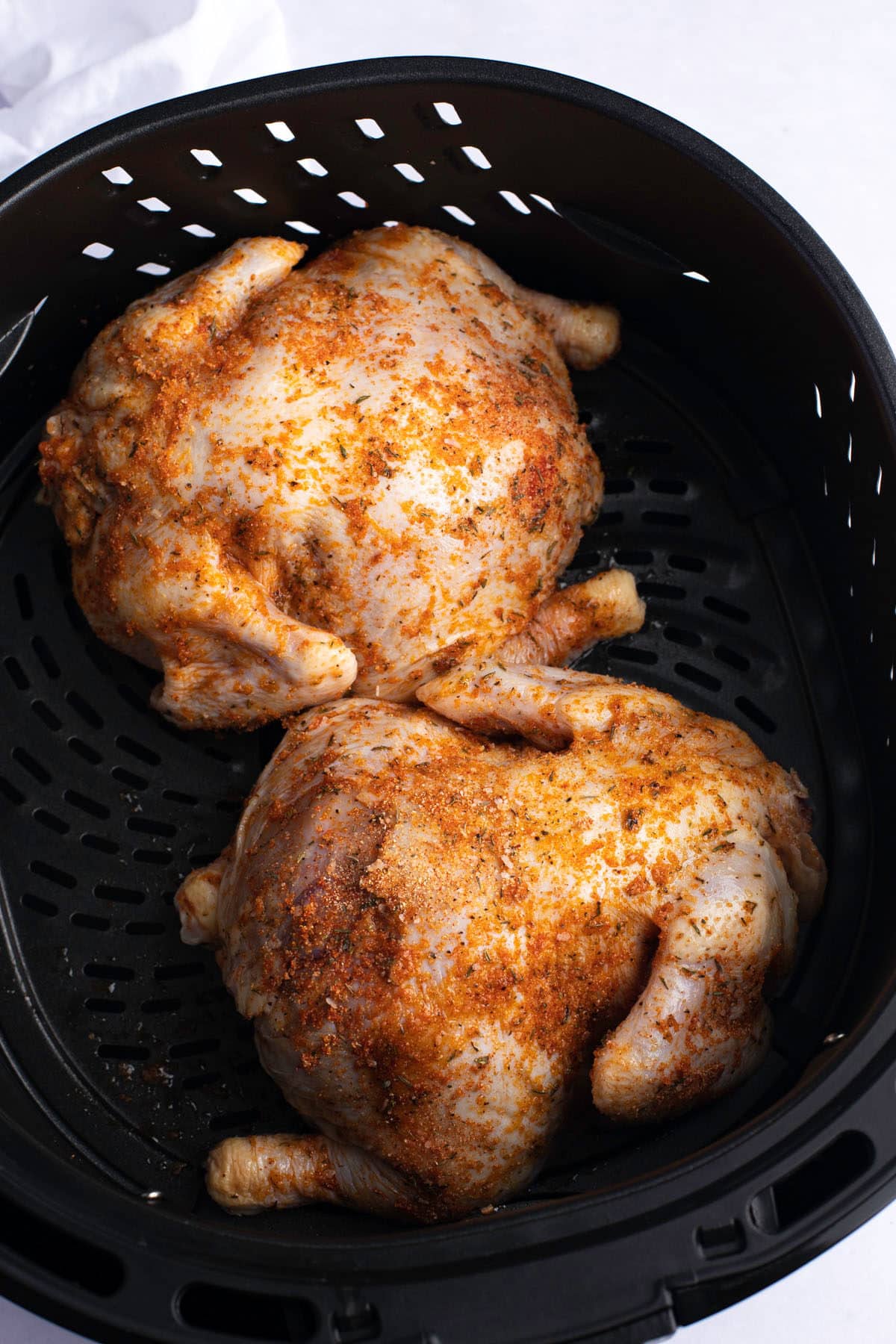Two cornish hens in the air fryer basket.