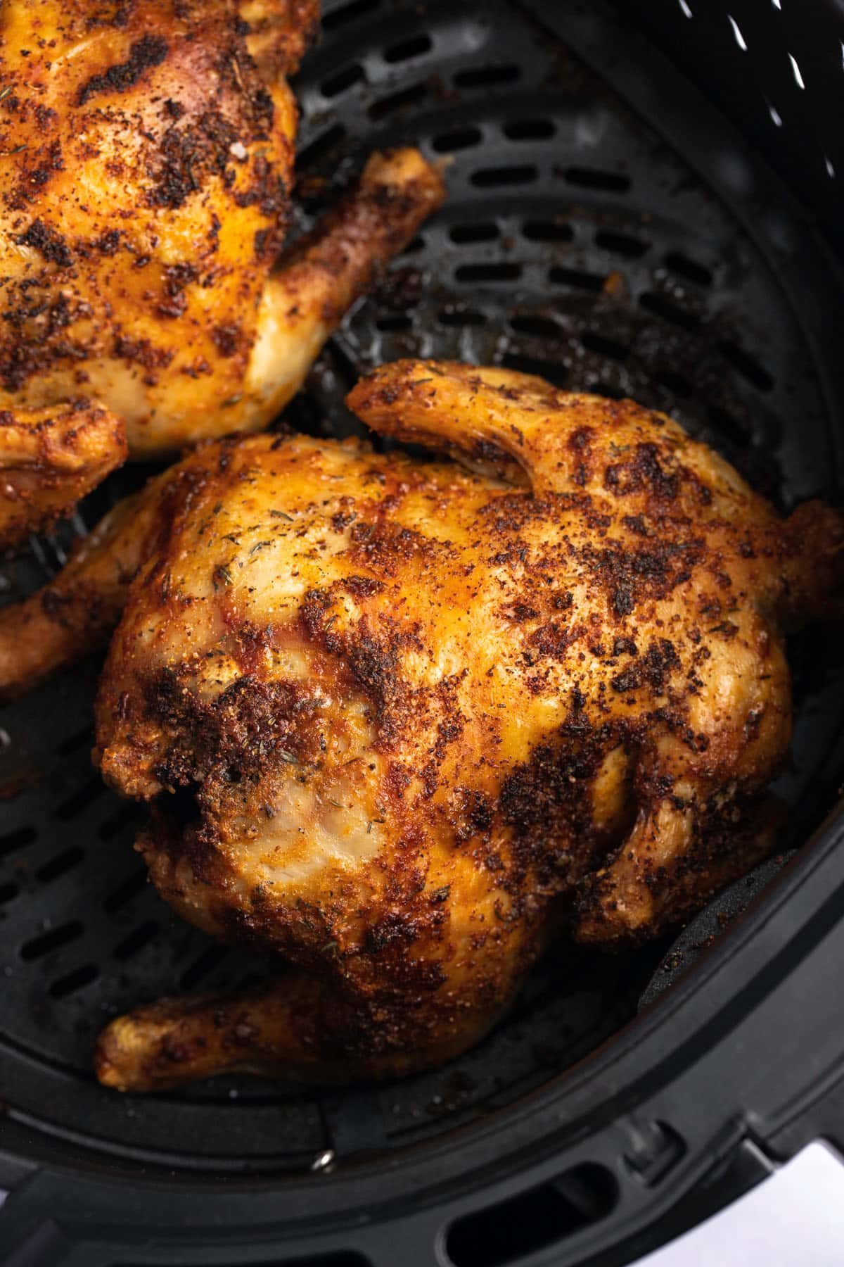 A cooked cornish hen in the air fryer basket.