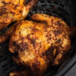 A cooked cornish hen in the air fryer basket.