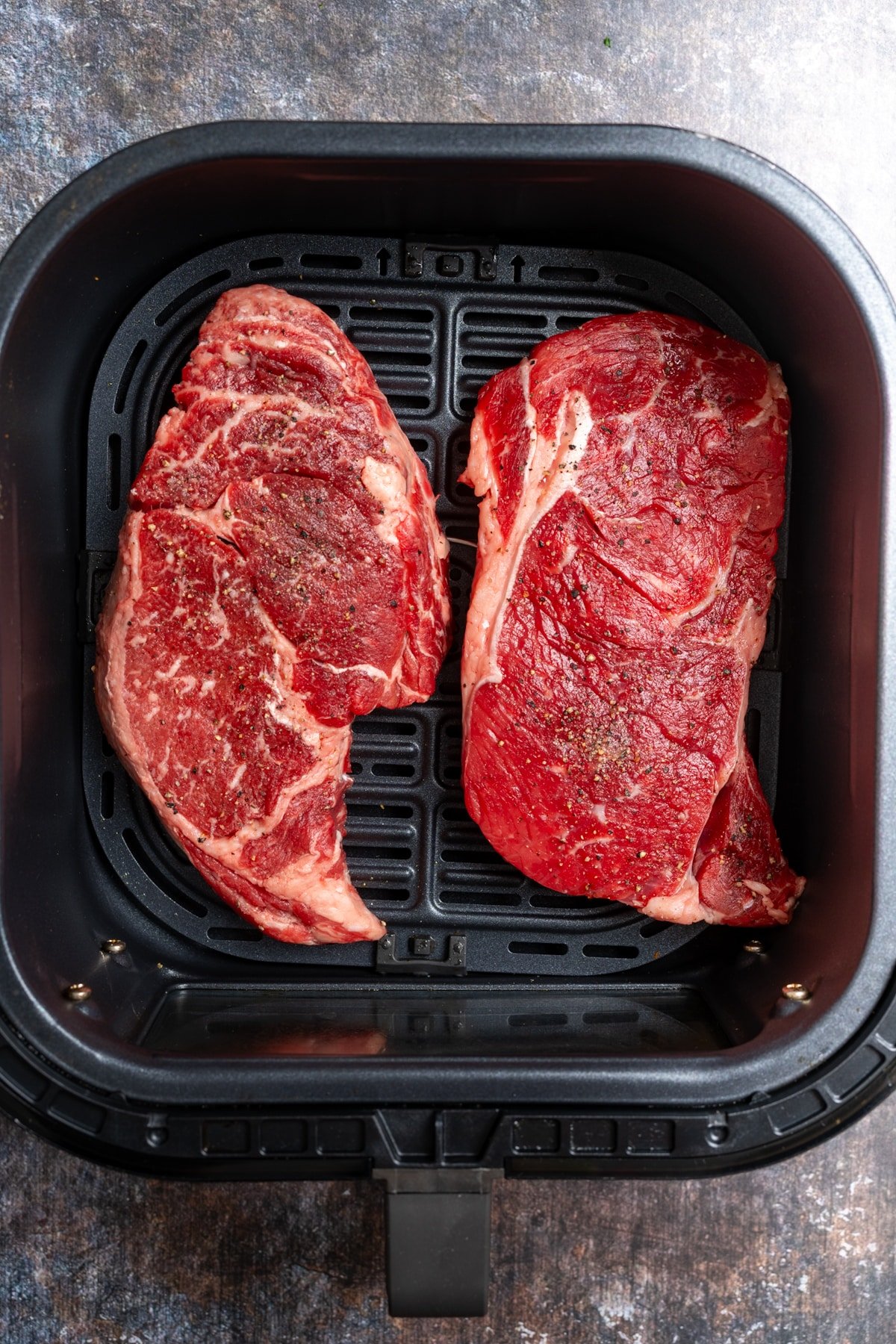 raw steaks in air fryer basket