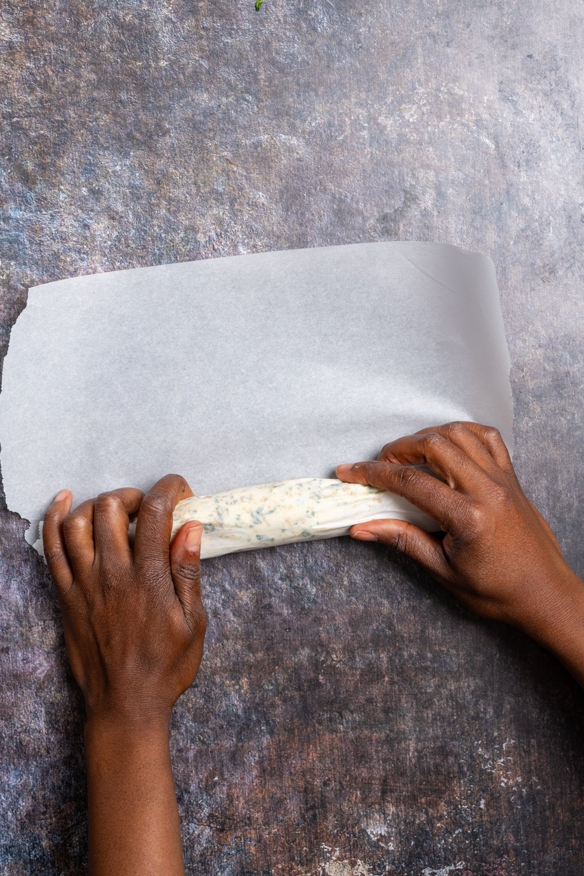 hands rolling garlic butter in parchment paper