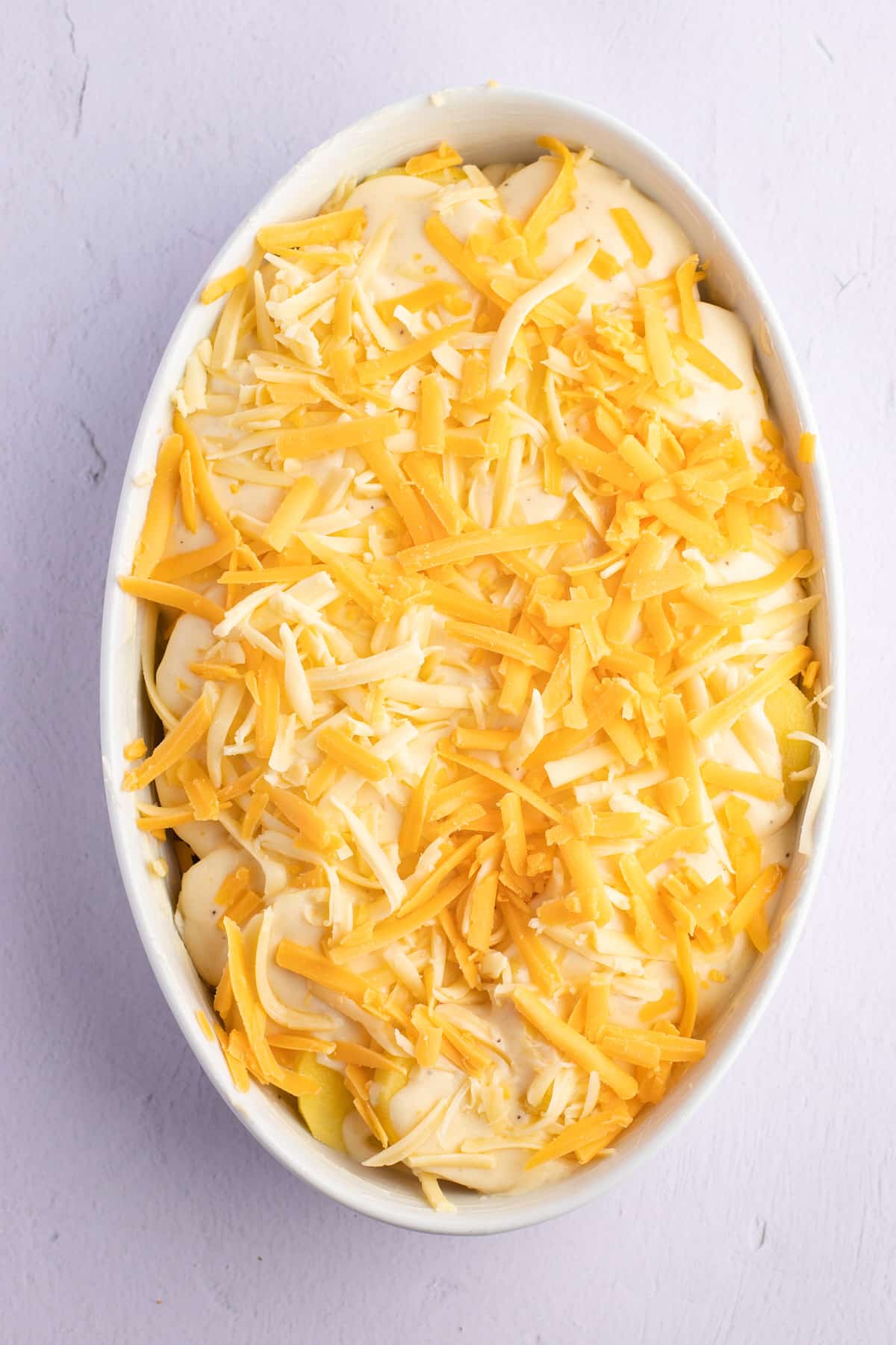 Shredded cheese placed on top of the cram and potatoes.