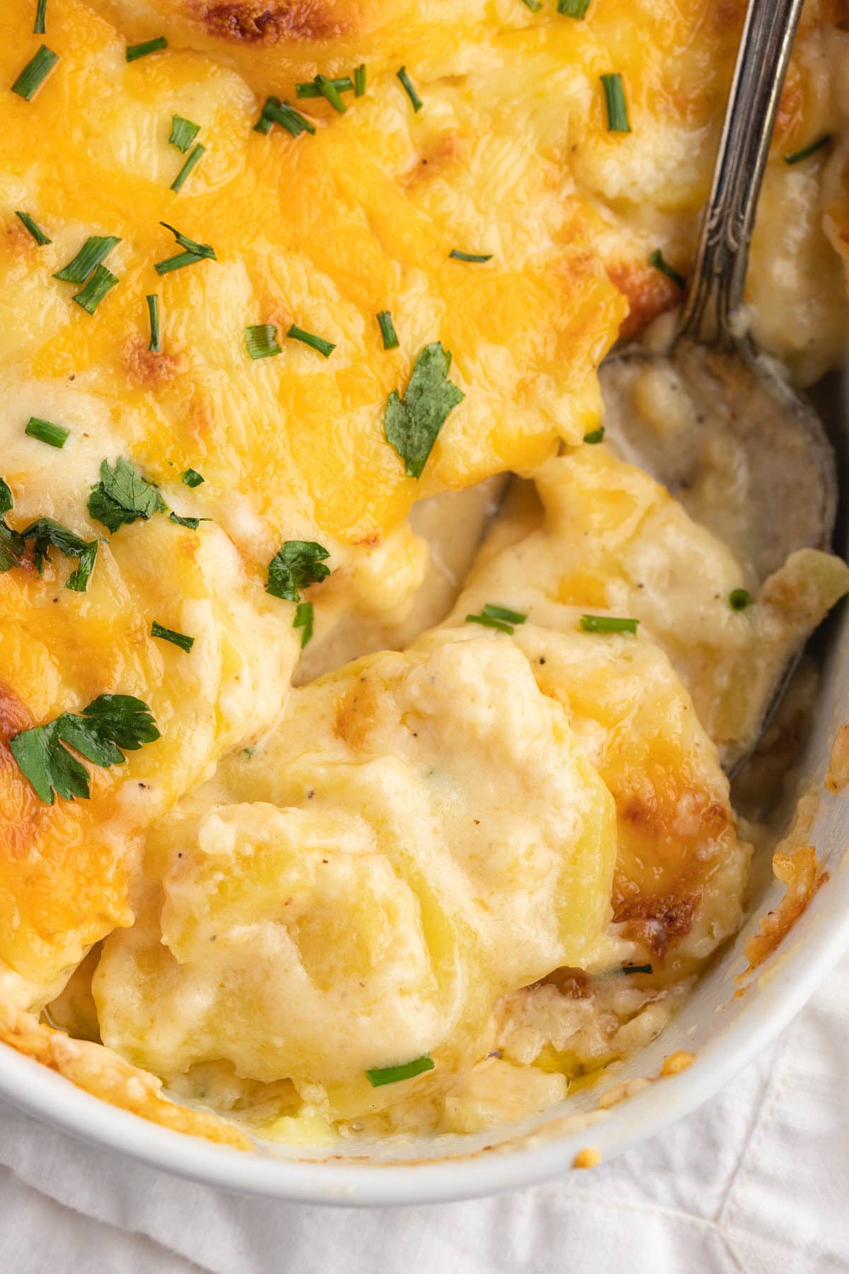 Close up of a serving spoon in the scalloped potatoes.