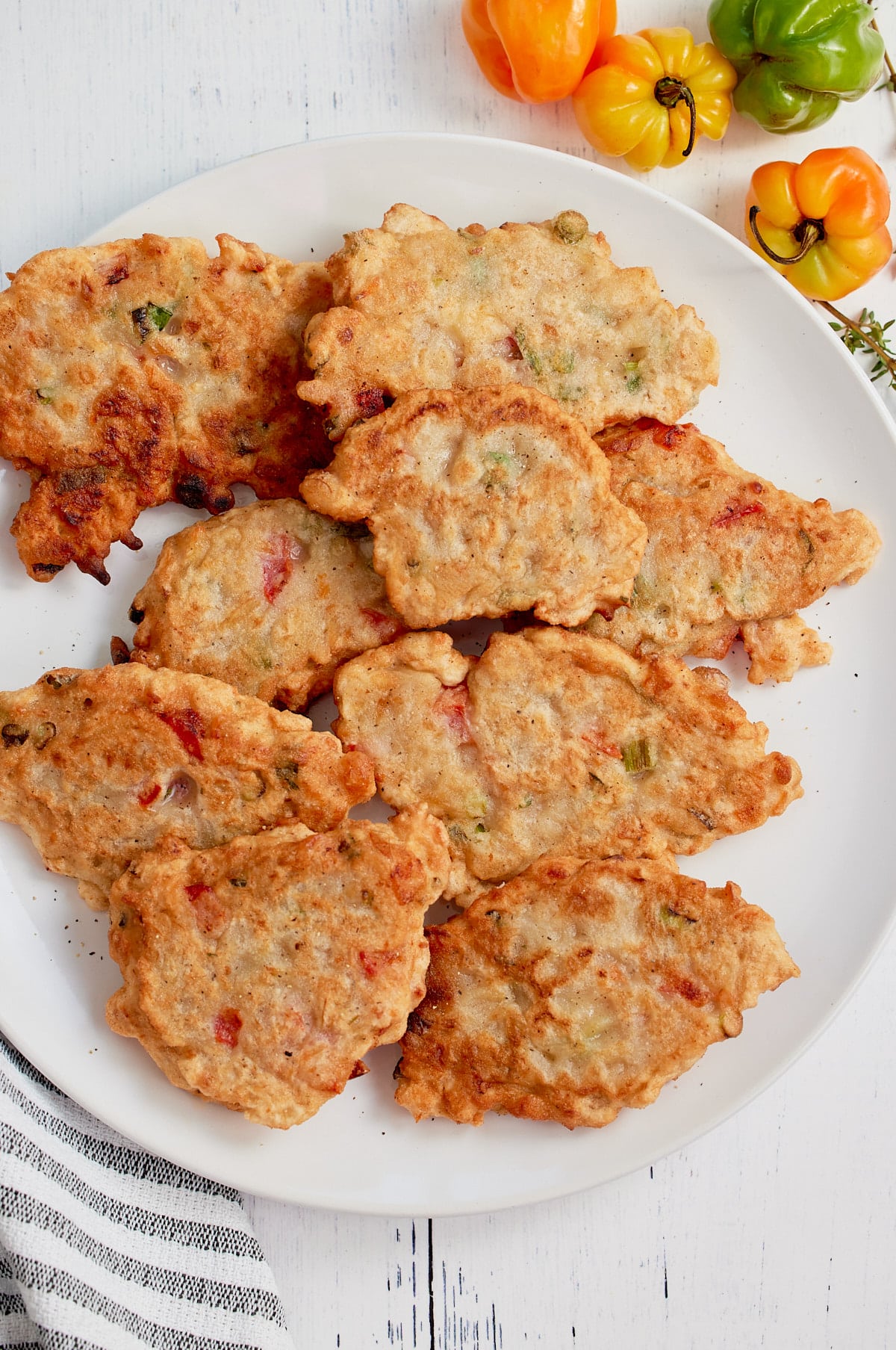 fritters on white pate with peppers around it