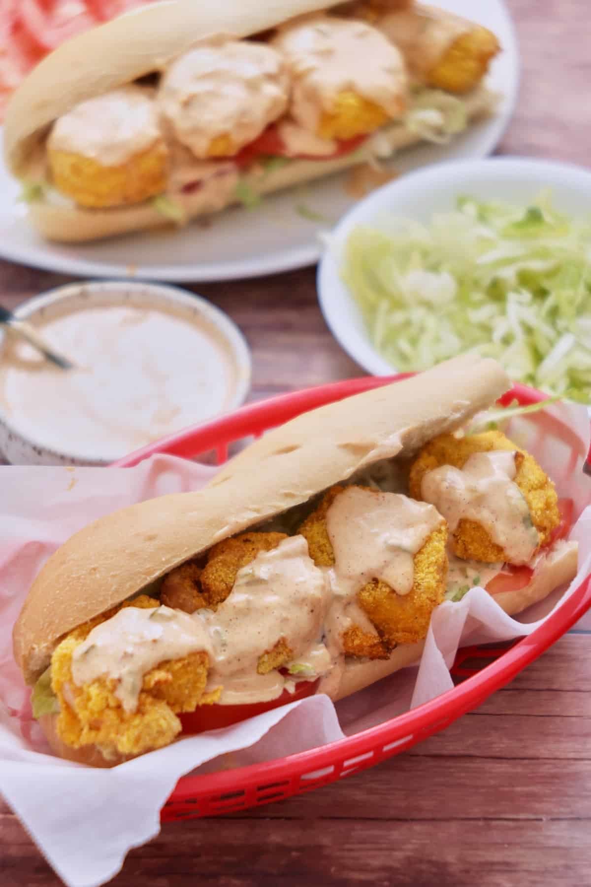 Two air fryer shrimp po'boy sandwiches in red serving baskets lined with parchment.