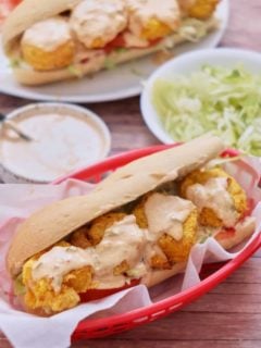Two air fryer shrimp po'boy sandwiches in red serving baskets lined with parchment.