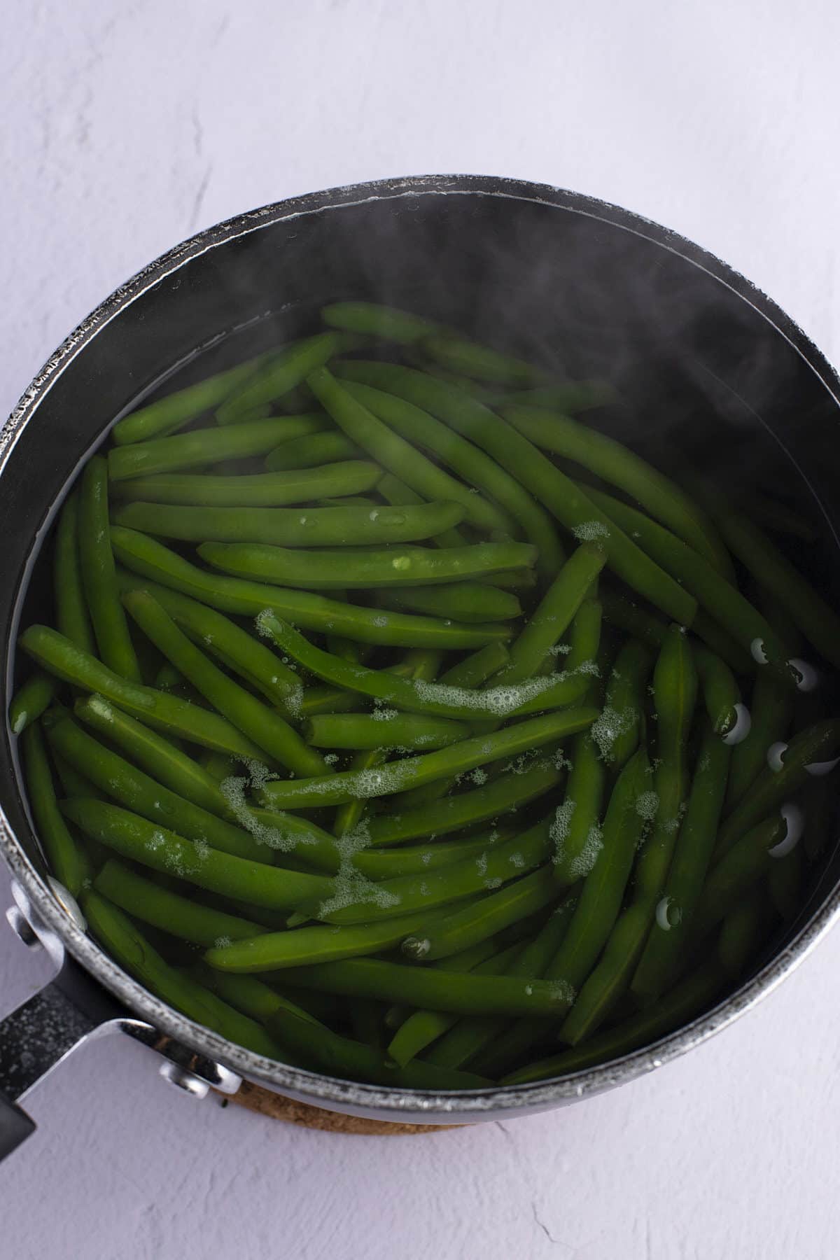 Blanching green beans in a pot.