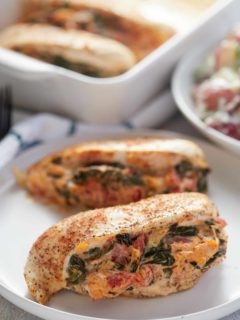 Two spinach stuffed chicken breasts served on a white plate.