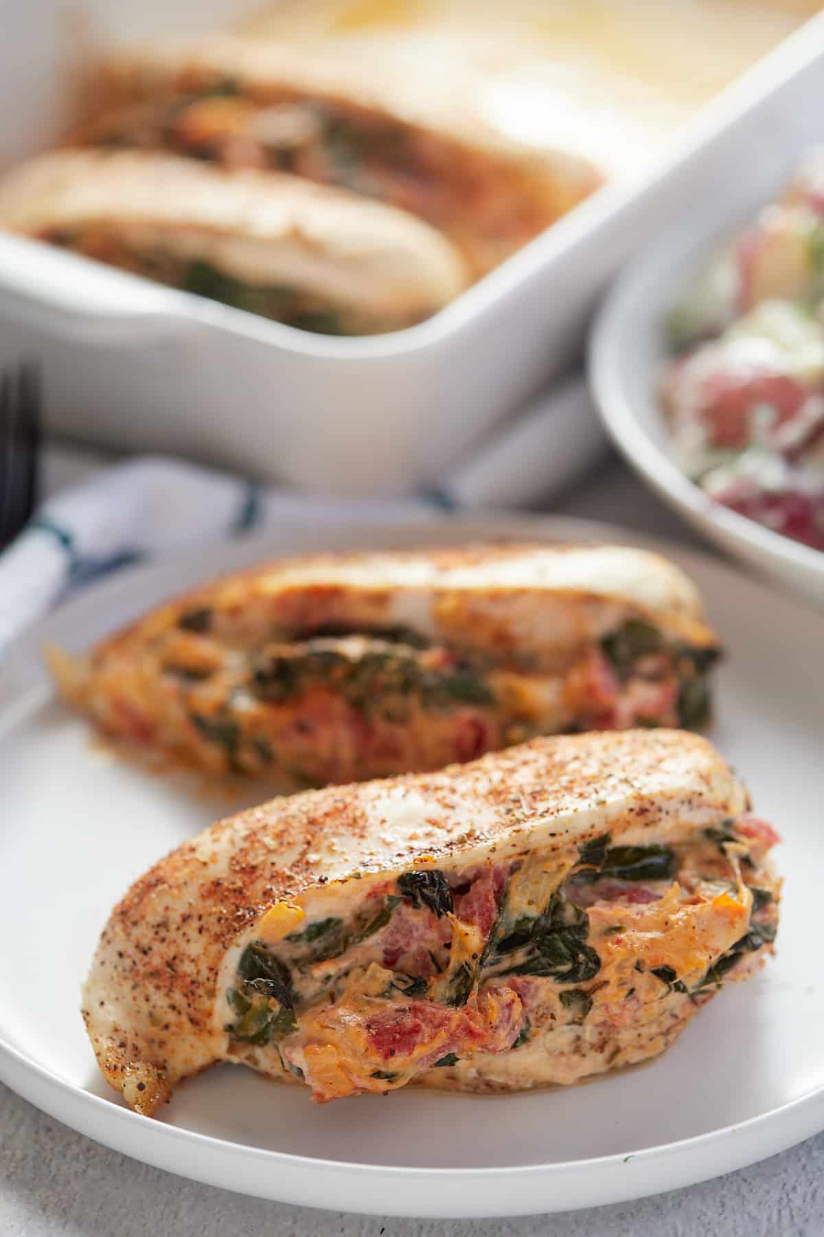 Two spinach stuffed chicken breasts served on a white plate.