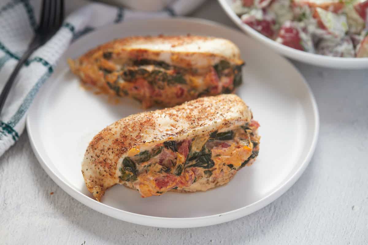 Stuffed chicken breasts served on a plate next to a kitchen cloth.