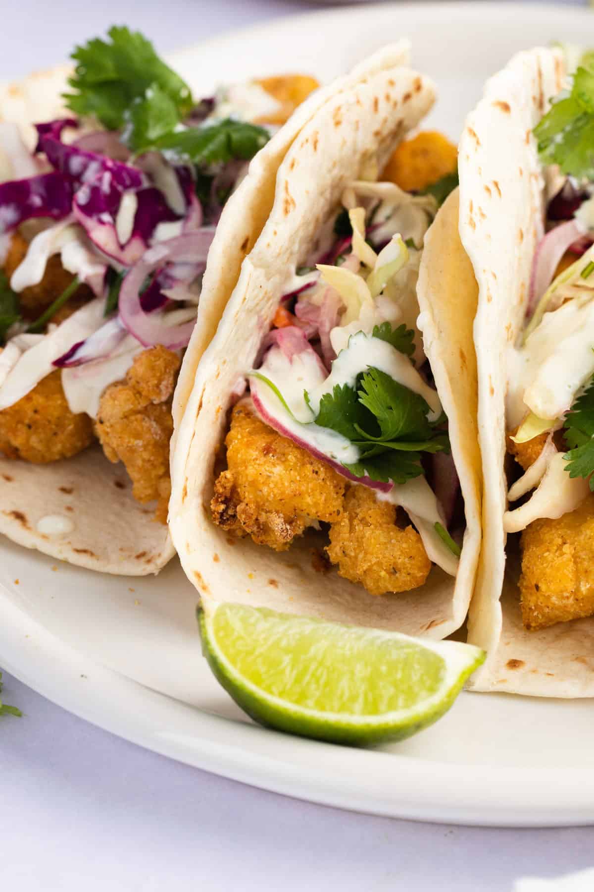 Close up of an air fried fish taco next to a lime wedge.