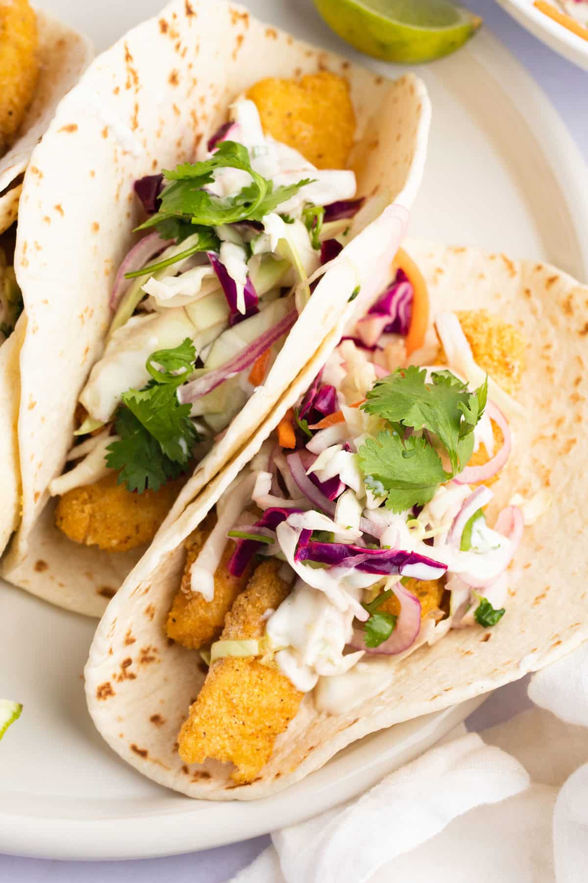 Fish tacos topped with slaw and lime crema.