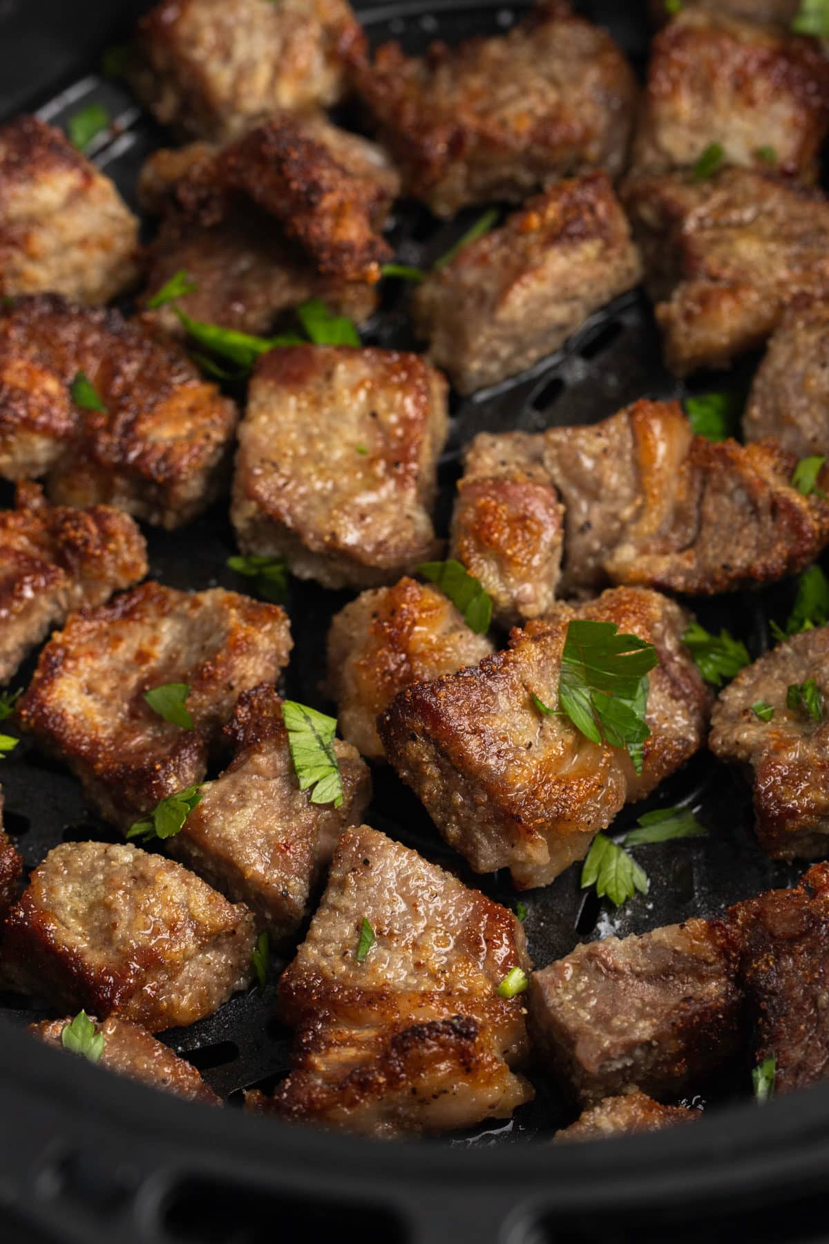 Close up of steak bites garnished with fresh herbs.