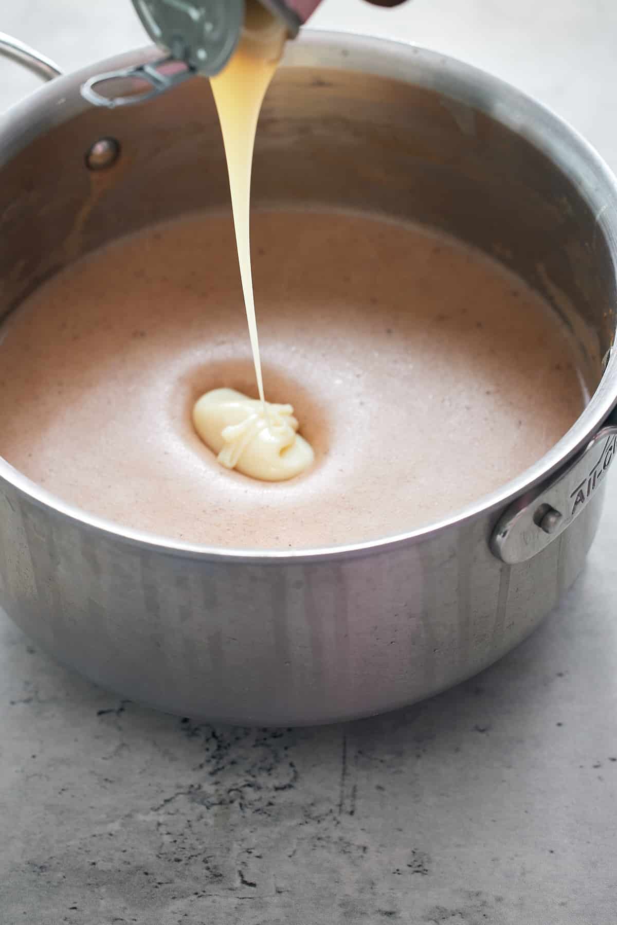 condensed milk being added to pot of green banana porridge