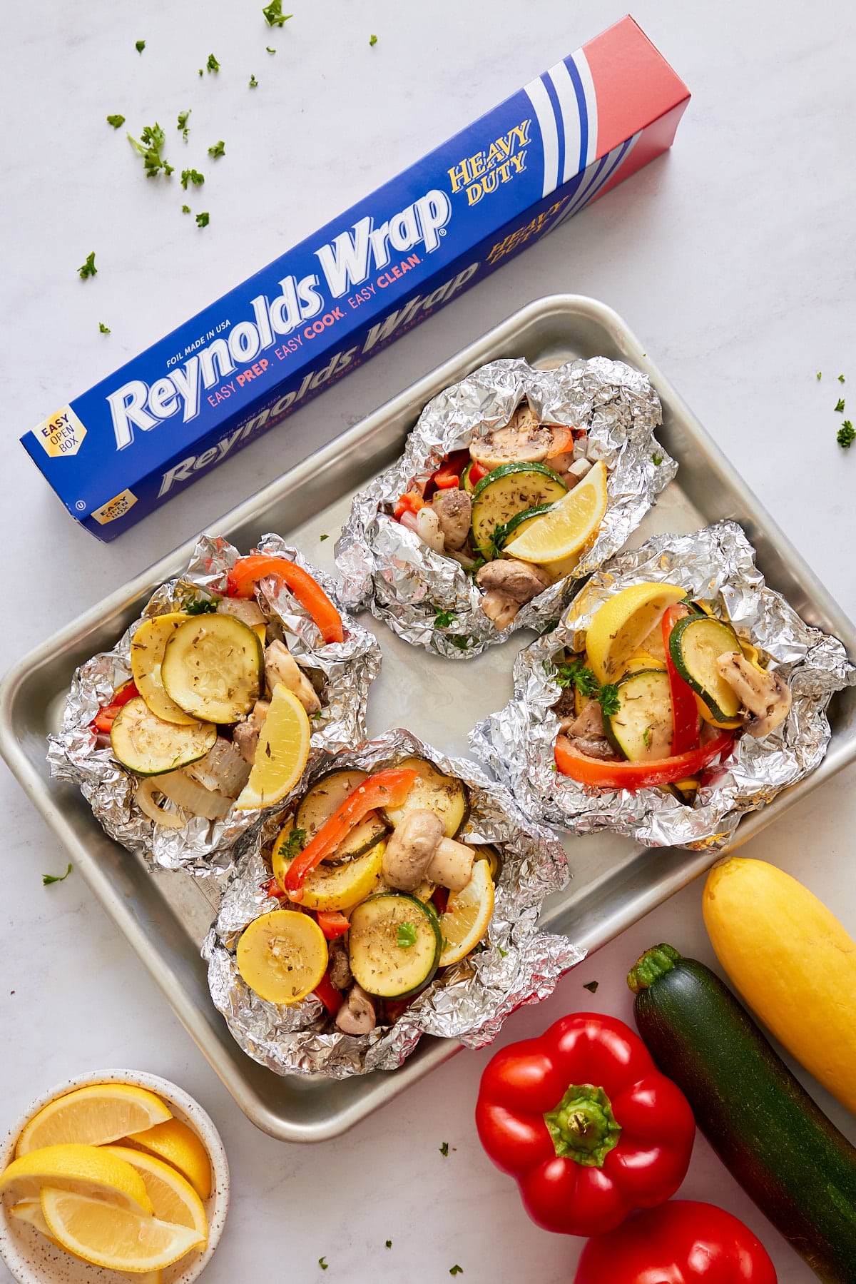 vegetables in foil packets on sheet pan with reynolds wrap box on side