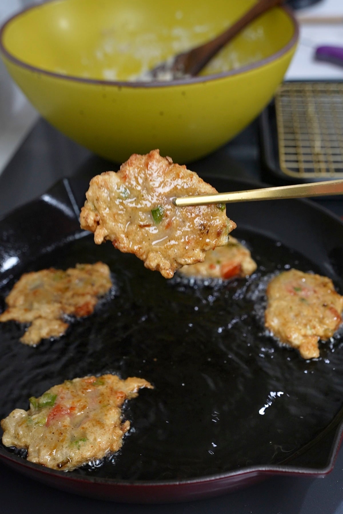 fried saltfish being picked up out of oil in skillet
