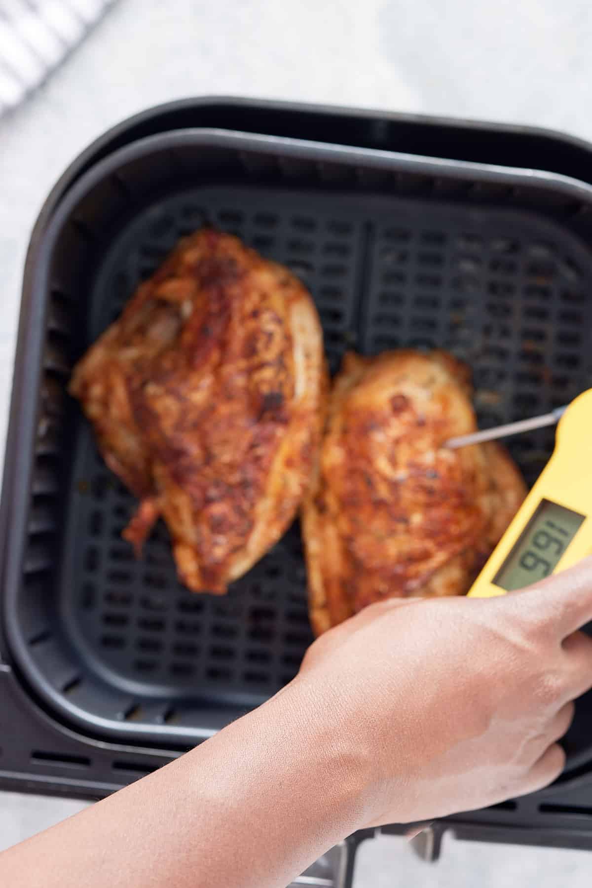 thermometer checking temperature of bone in chicken breasts