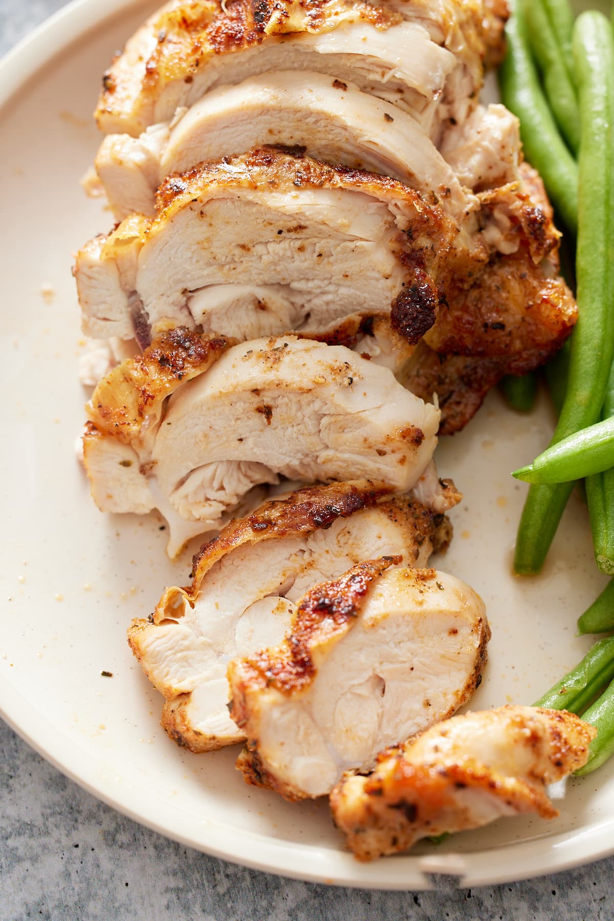 sliced chicken breasts on plate with green beans on side