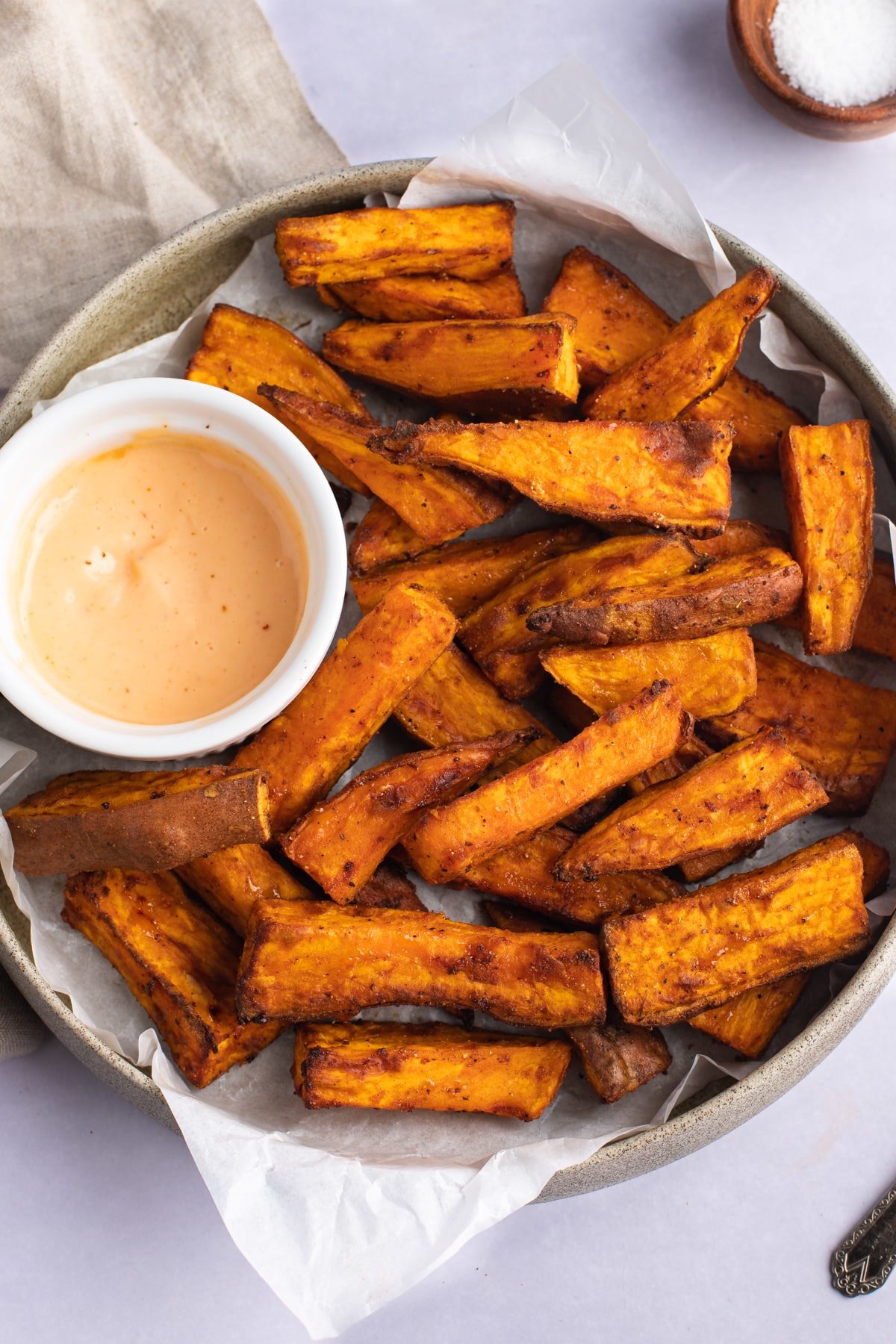 Air fryer sweet potato wedges on a plate with a dip.