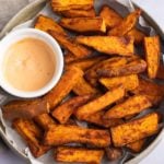 Air fryer sweet potato wedges on a plate with a dip.