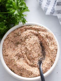 homemade spice blend mixed with spoon sticking out and parsley on left