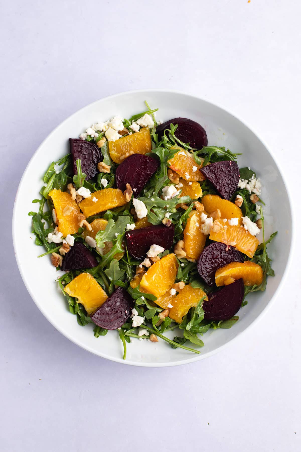 The salad tossed together in a white bowl.