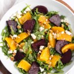 Overhead shot of roasted beet and orange salad in a white bowl.
