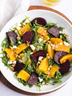 Overhead shot of roasted beet and orange salad in a white bowl.