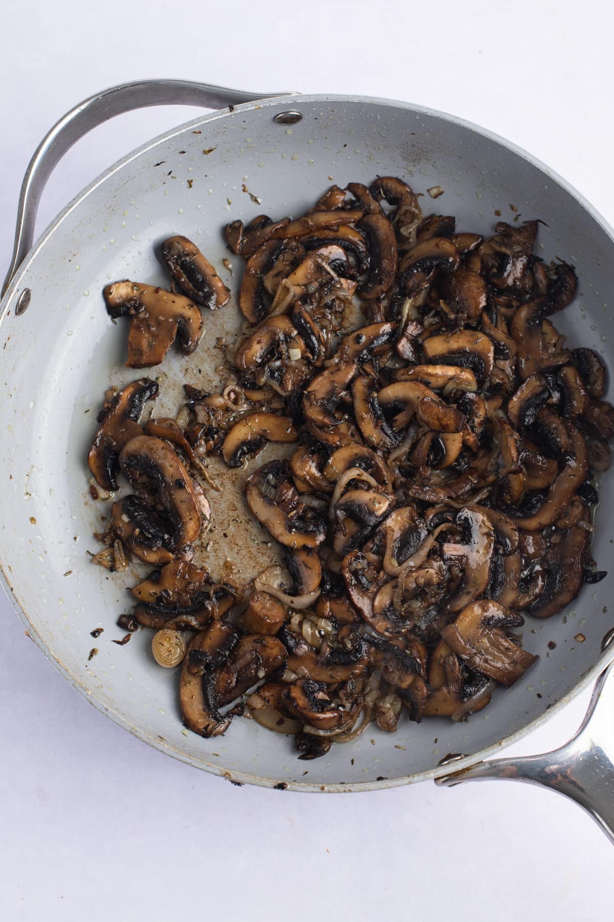 Mushrooms being browned in a skillet.