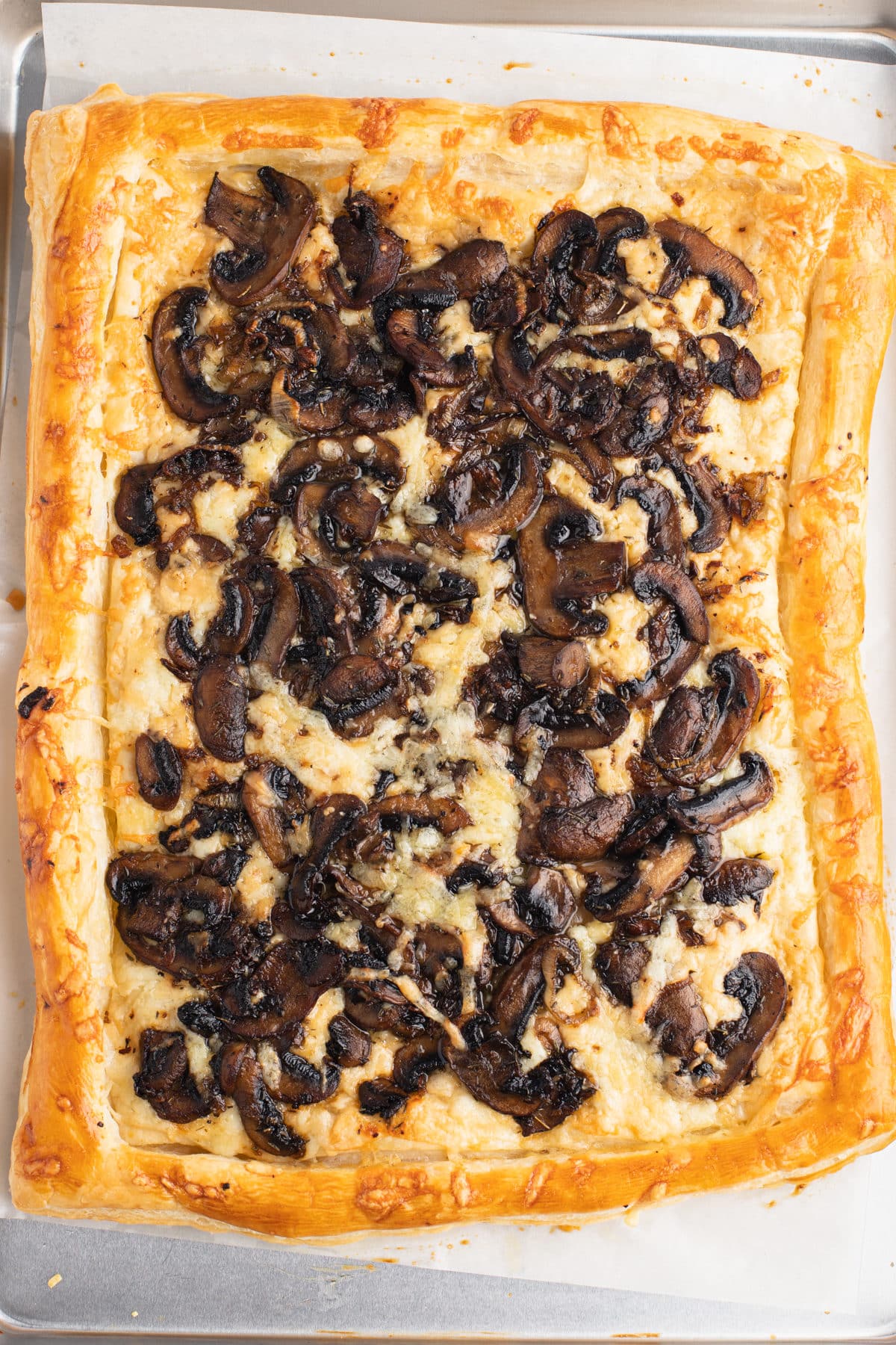 Cheese and mushrooms topping a puff pastry sheet.