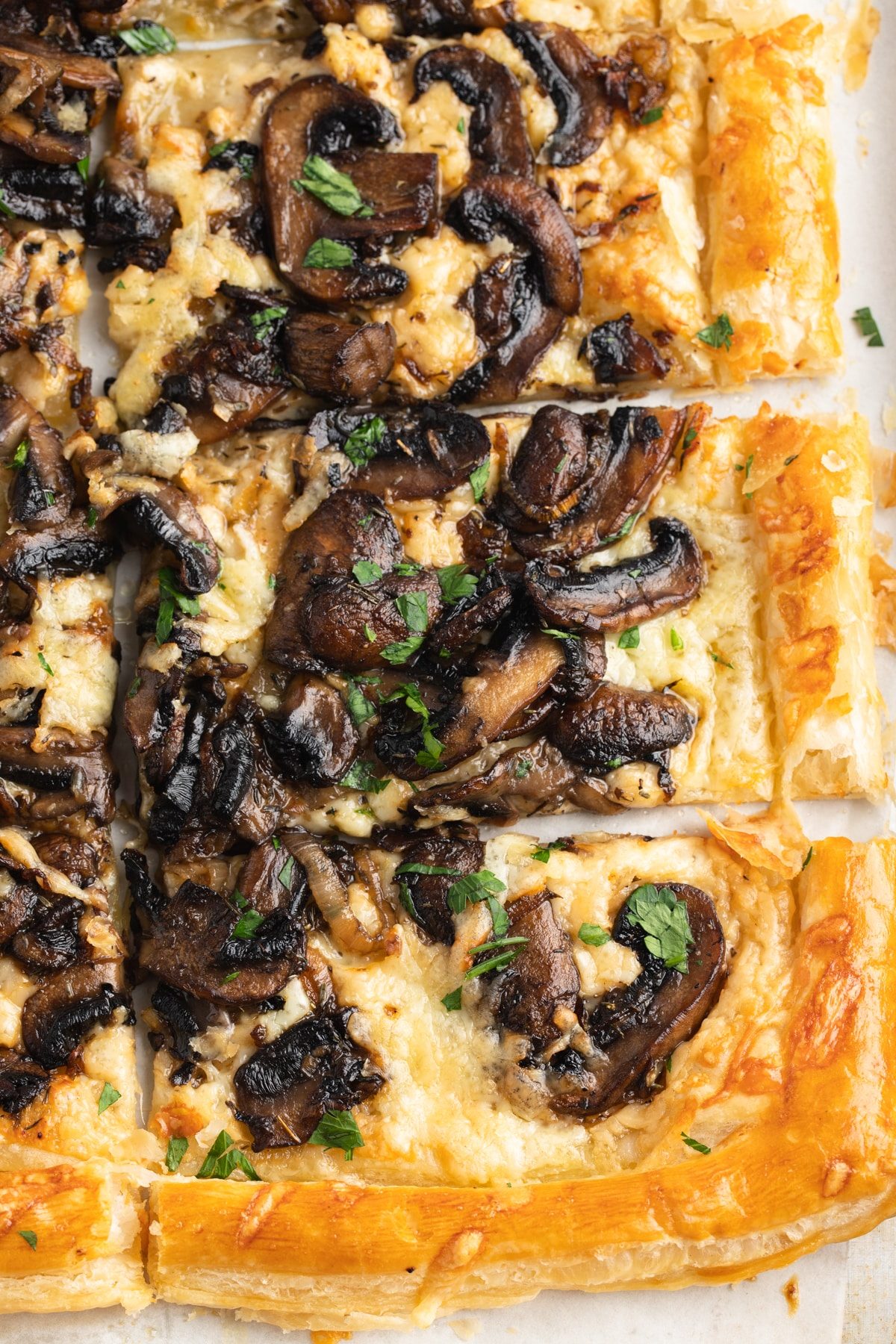 A mushroom tart cut into squares to serve.