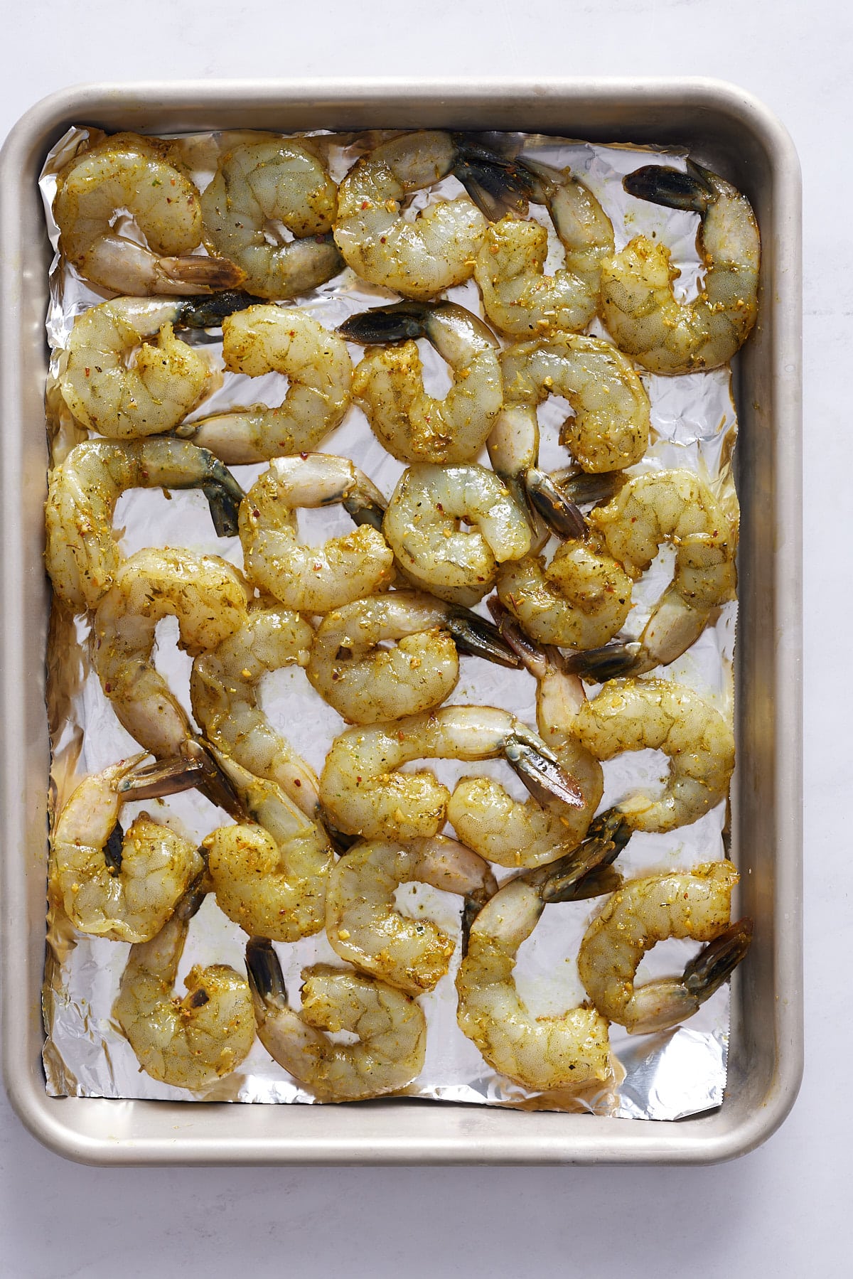 raw and seasoned shrimp on baking sheet