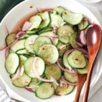 Southern cucumber salad with red onion in a bowl with wooden salad spoons.