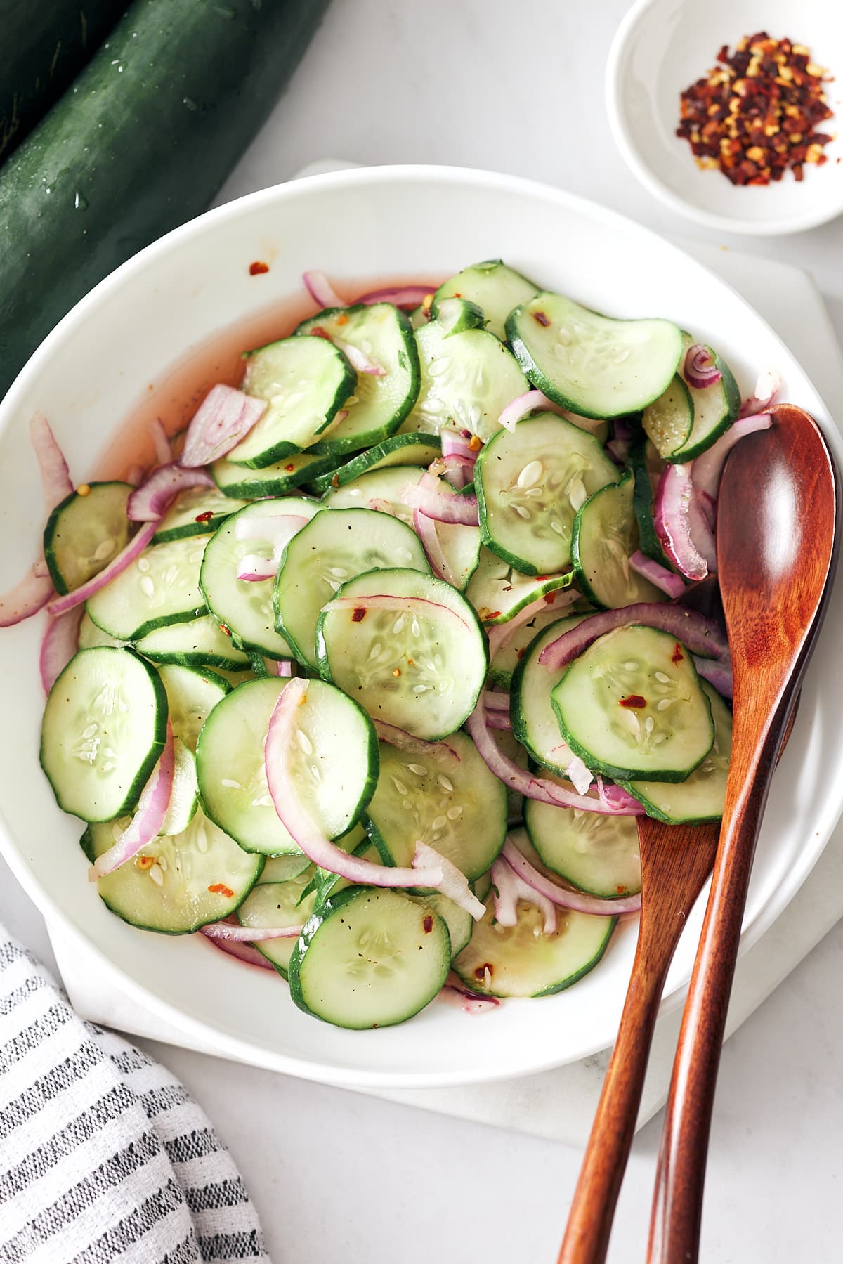 Southern cucumber salad with red onion in a bowl with wooden salad spoons.