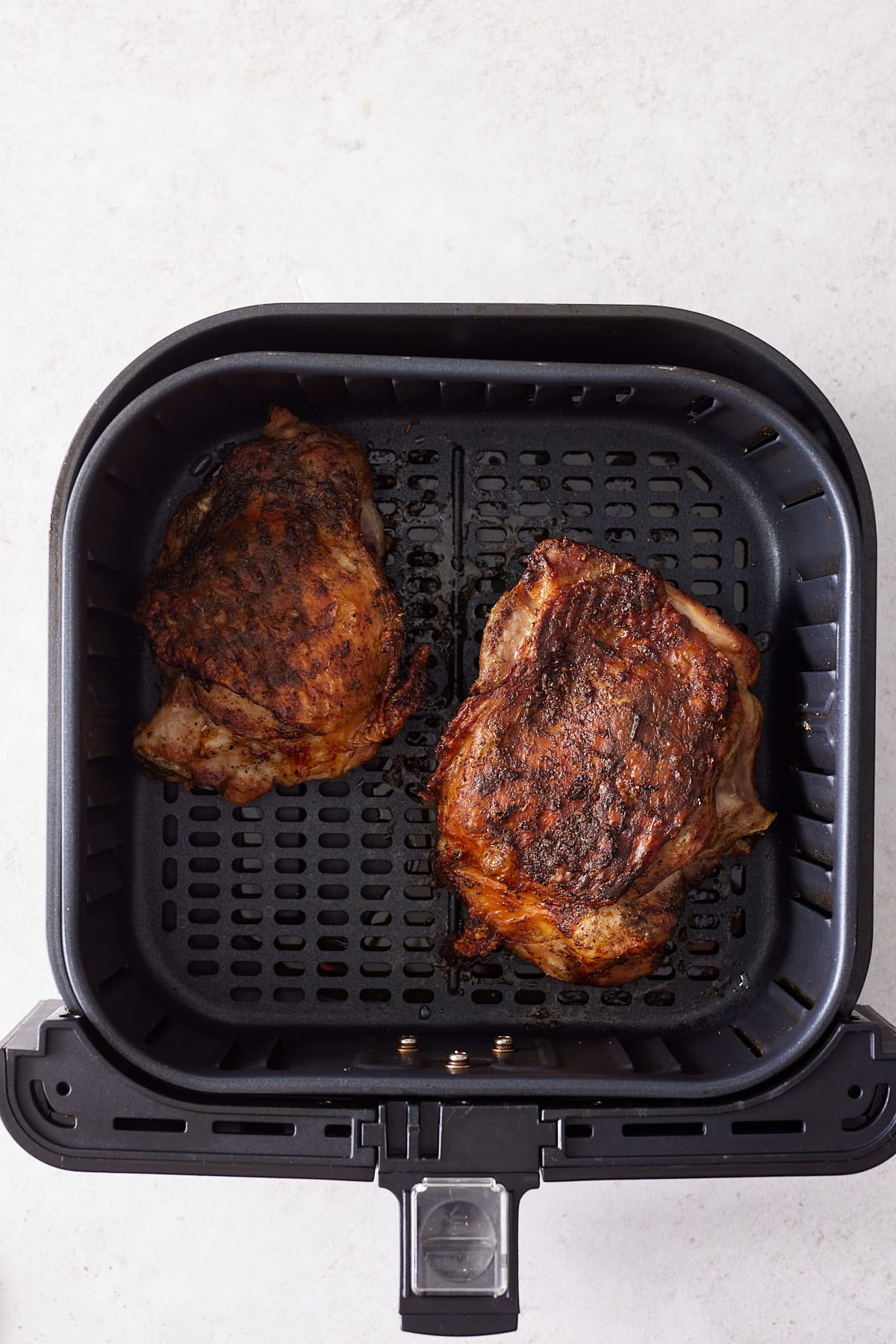 close up of 2 turkey thighs cooked through in air fryer basket