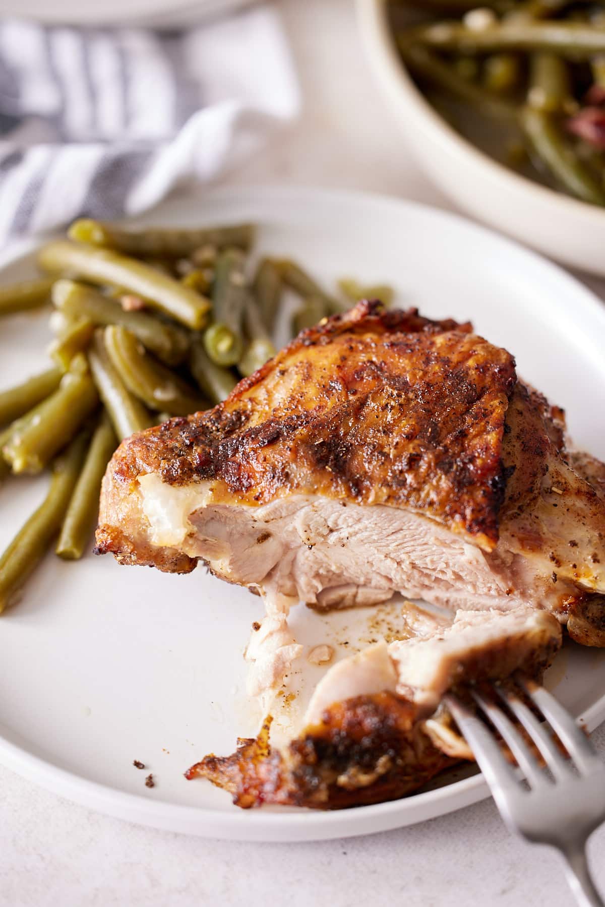 Air fried turkey thigh on a plate with green beans and a fork