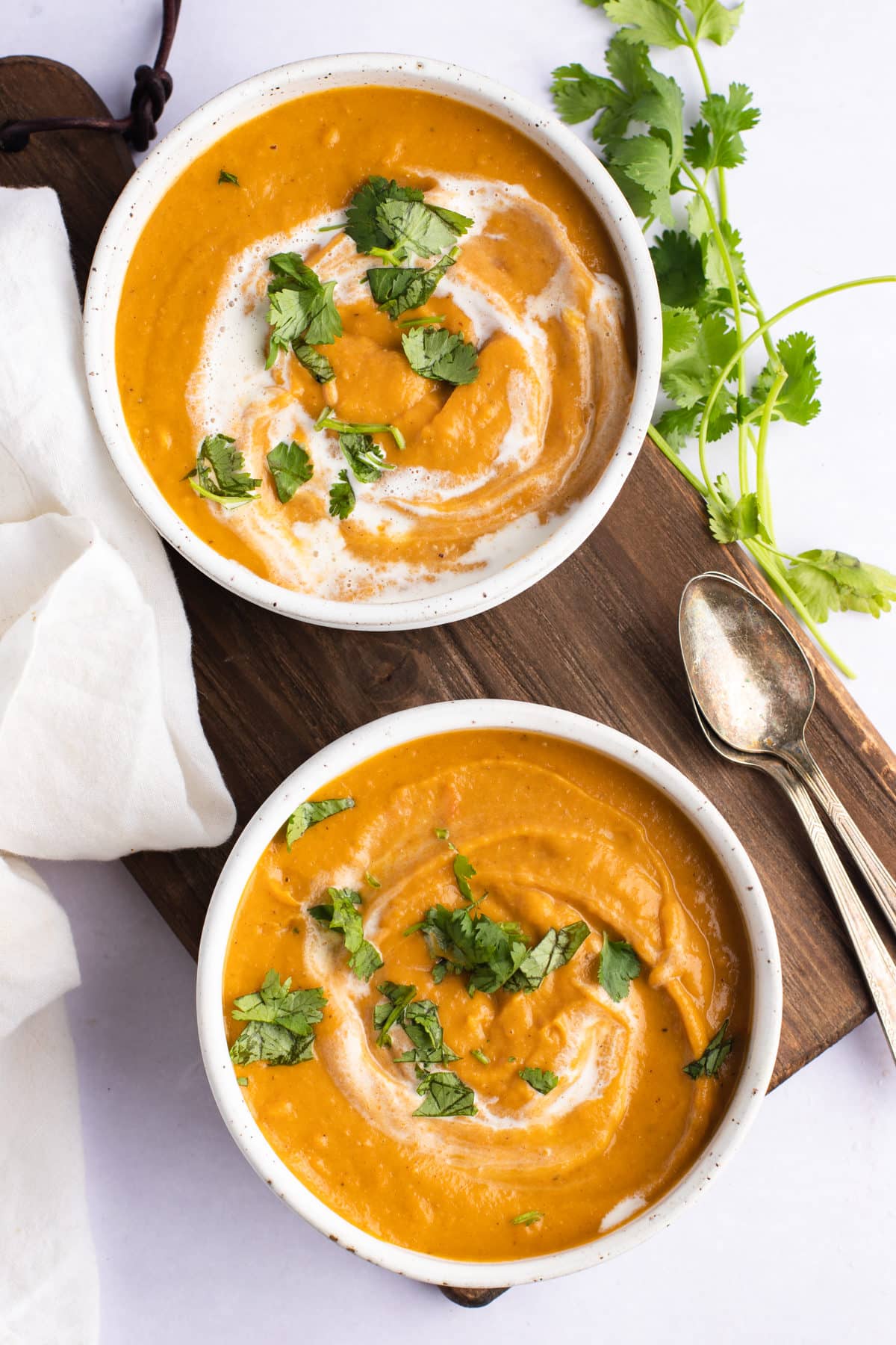 overhead of two bowl of carrot and lentil soup with cilantro garnish and two spoons