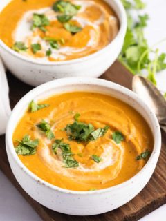 overhead of two bowl of carrot and lentil soup with cilantro garnish and two spoons