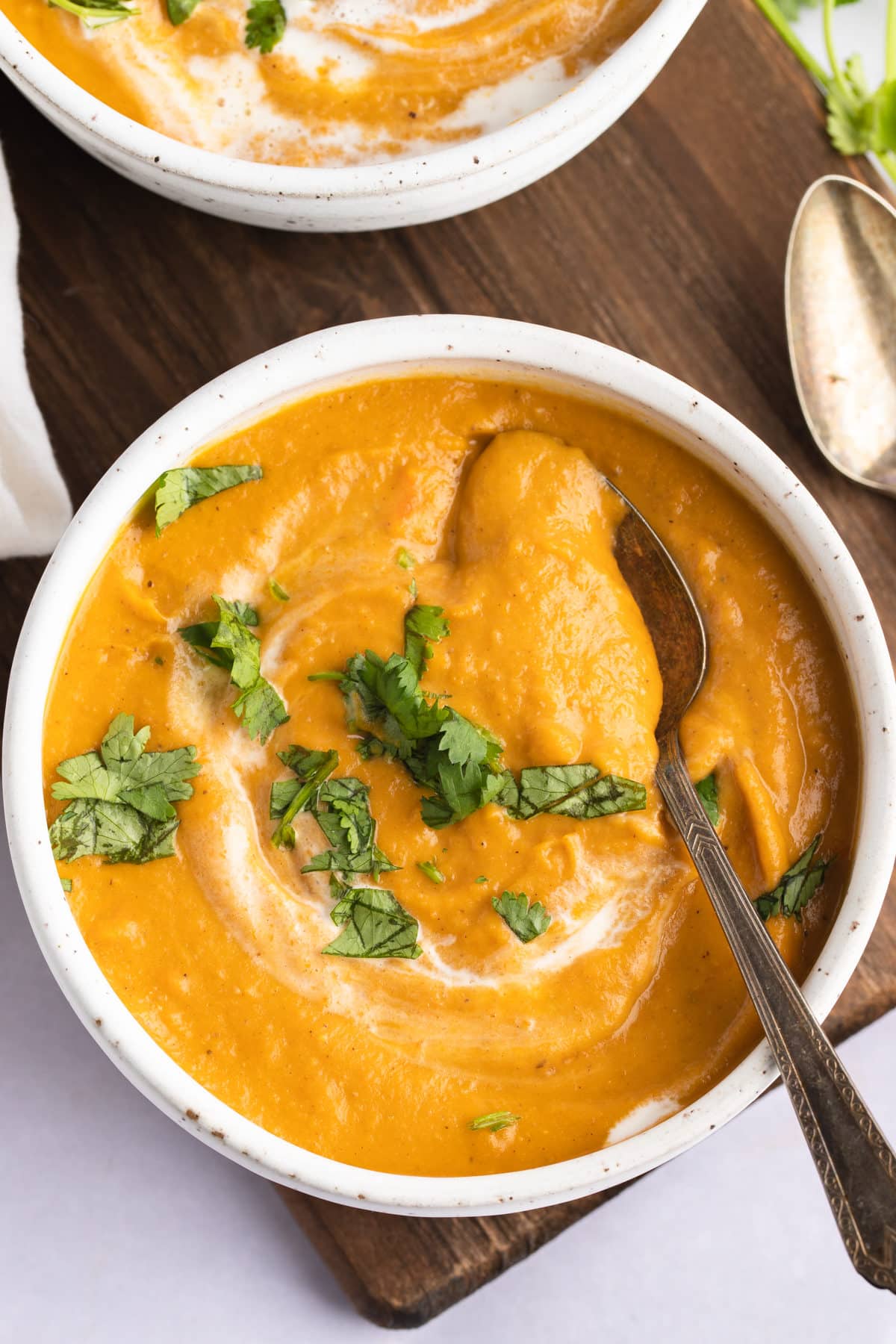 overhead of two bowl of carrot and lentil soup with cilantro garnish and two spoons